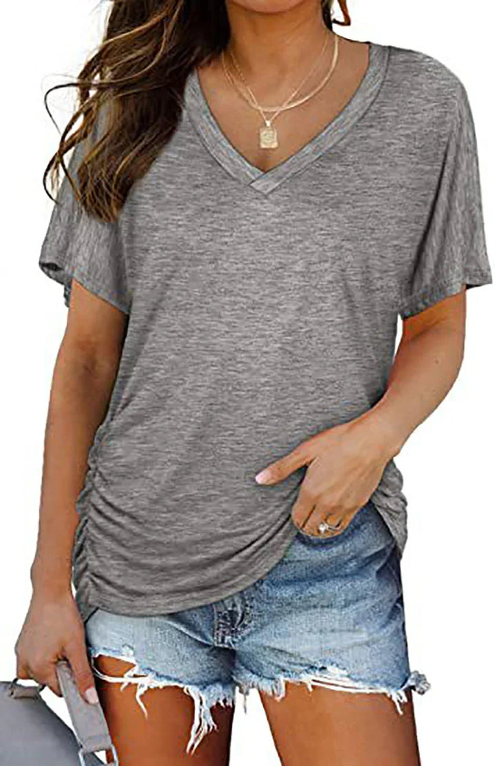 Woman wearing gray ruched V-neck T-shirt paired with distressed denim shorts and layered gold necklaces