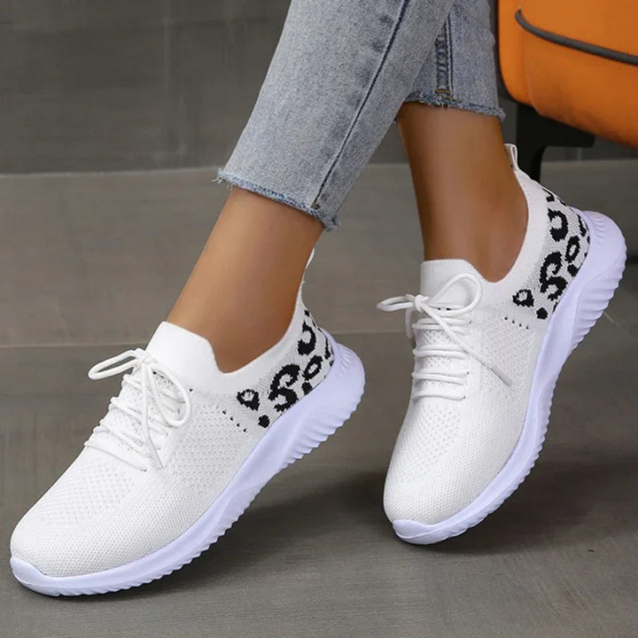 White knitted lace-up sneakers with black leopard print detail worn with light blue jeans