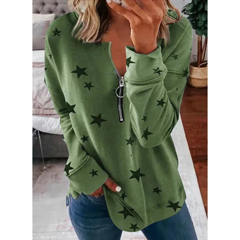 Woman wearing green star print zip-up sweatshirt with long sleeves and blue jeans indoors