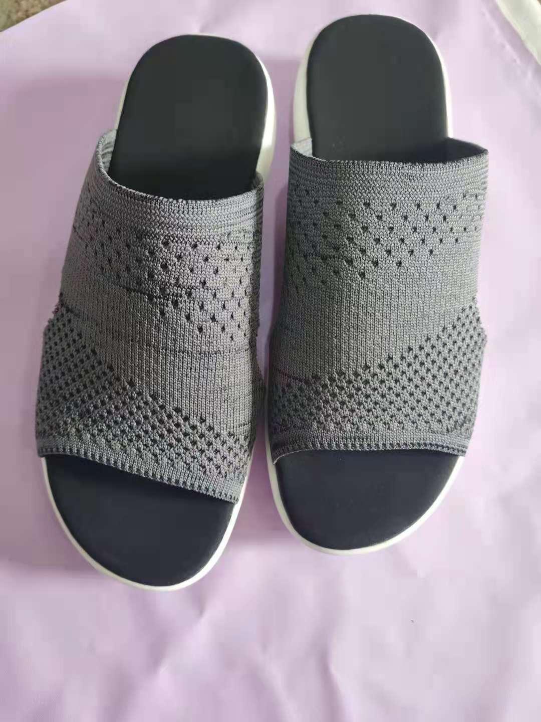 Pair of black and grey knitted slip-on sandals on a pink background