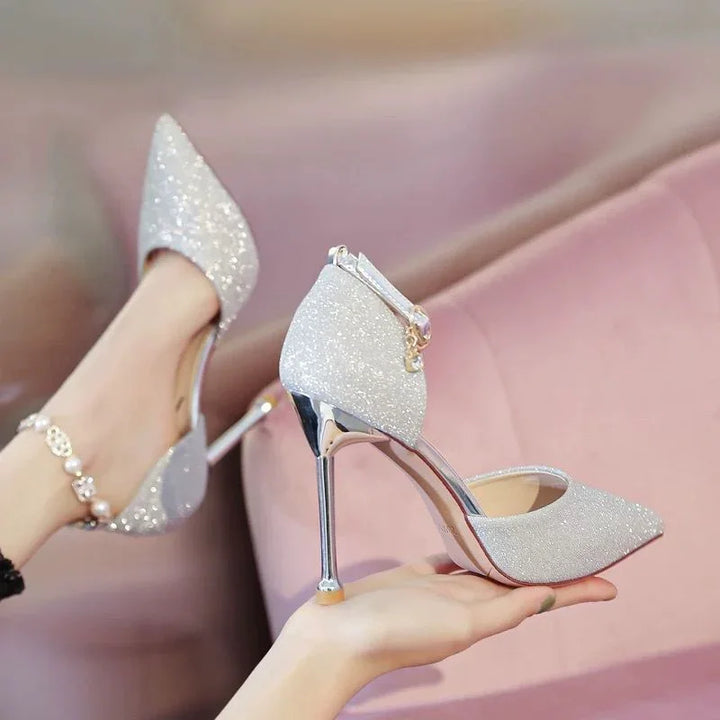 Silver glitter high heel shoes with ankle strap and metallic stiletto heel on a pink background
