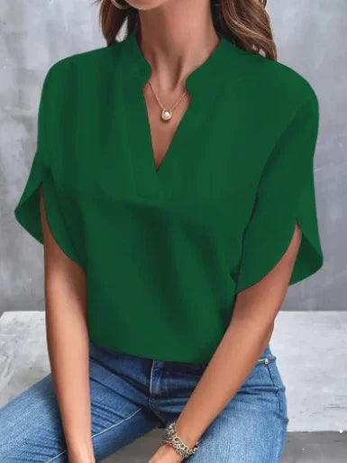 Woman wearing green stylish V-neck blouse with short sleeves and casual blue jeans