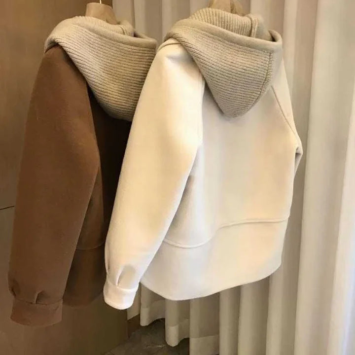 Brown and white hooded sweatshirts with ribbed knit hoods hanging indoors on a curtain background