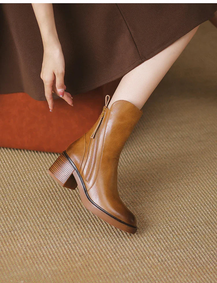 Woman wearing brown leather ankle boots with block heels and zipper detail on carpeted floor