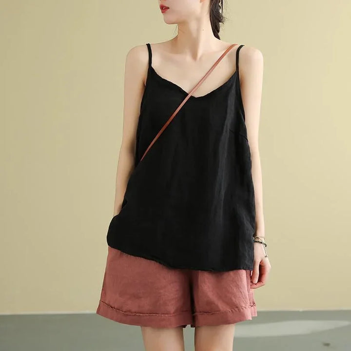 Woman wearing black sleeveless top and rust-colored shorts with crossbody bag strap