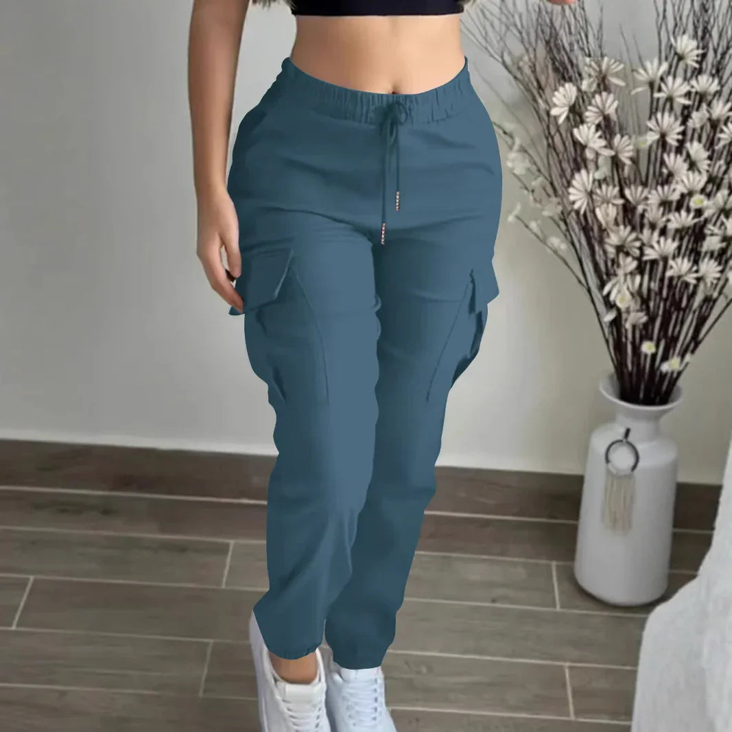 Woman wearing teal cargo jogger pants with drawstring waist and white sneakers indoors