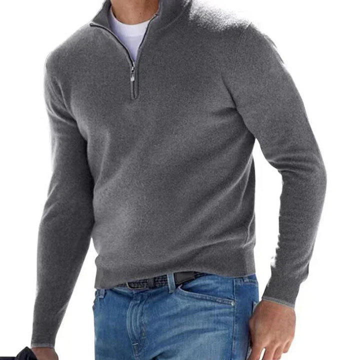Man wearing a grey quarter-zip sweater over a white T-shirt paired with blue jeans