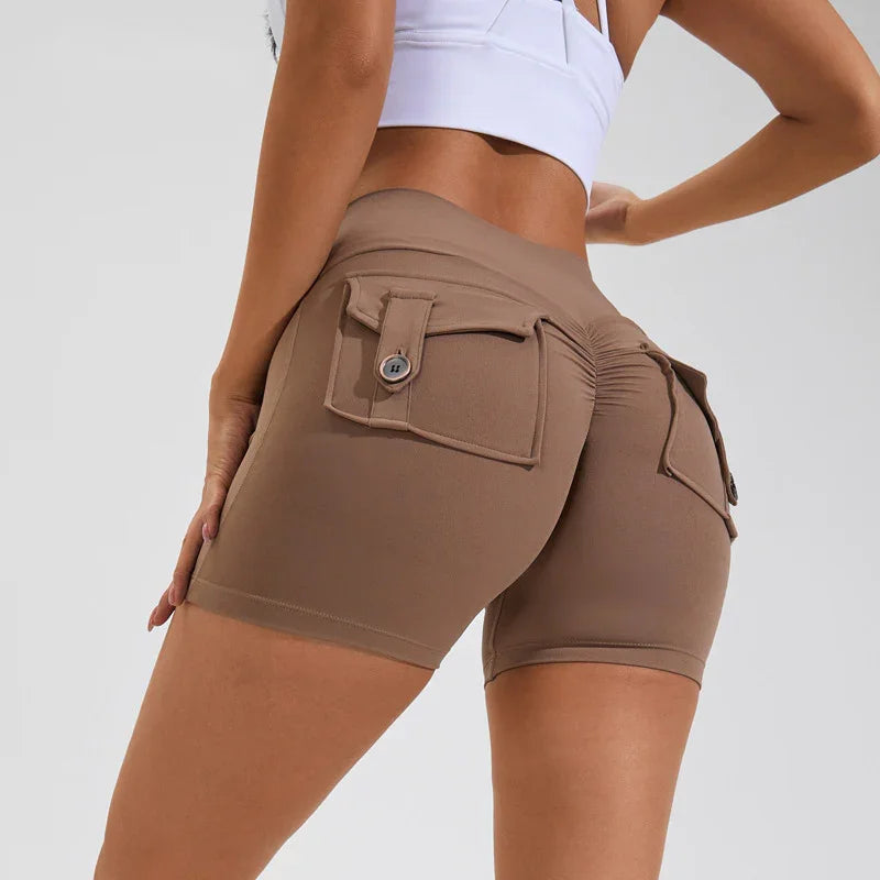 close-up of woman wearing brown ruched booty shorts with buttoned flap pockets and white crop top