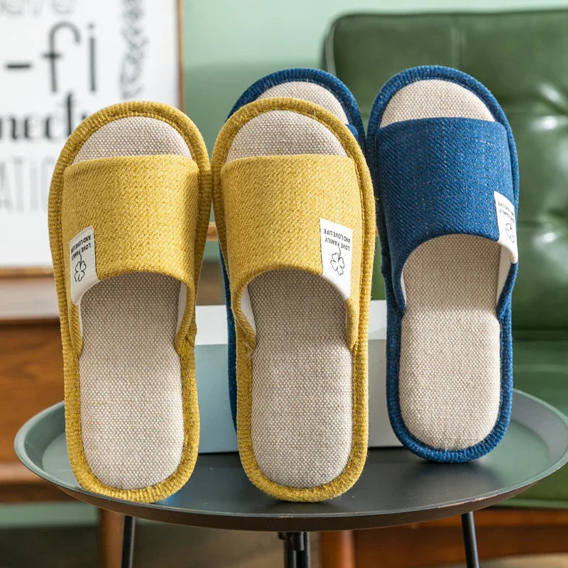 Comfortable indoor slippers in yellow and blue with soft fabric soles displayed on a round table