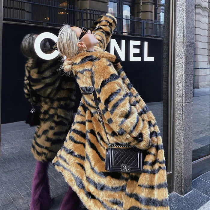 Woman in a tiger-striped fur coat posing in front of Chanel store window in urban setting