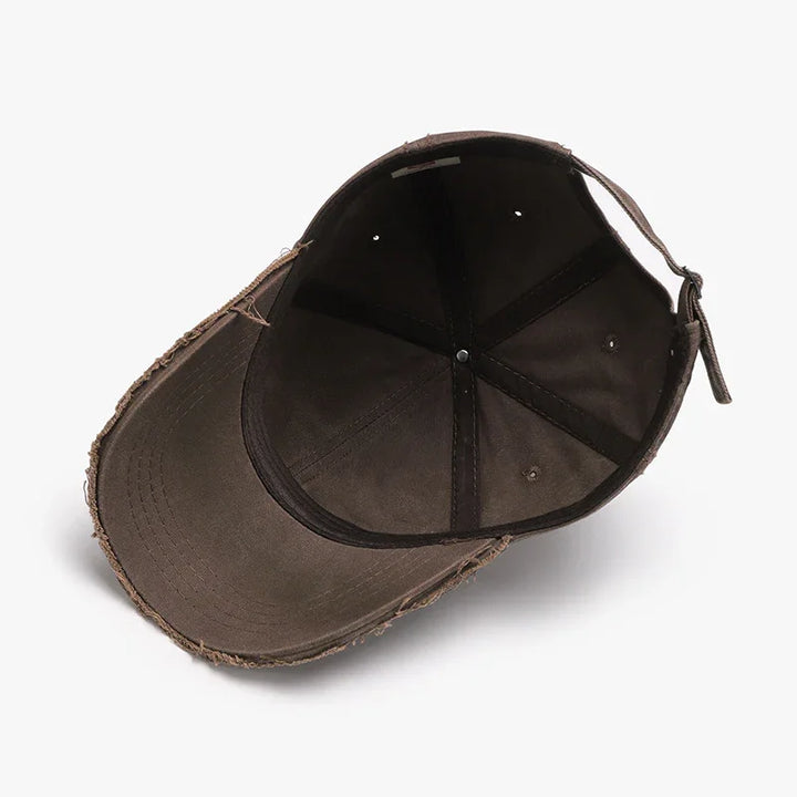 Inside view of a worn brown distressed baseball cap with an adjustable strap on white background
