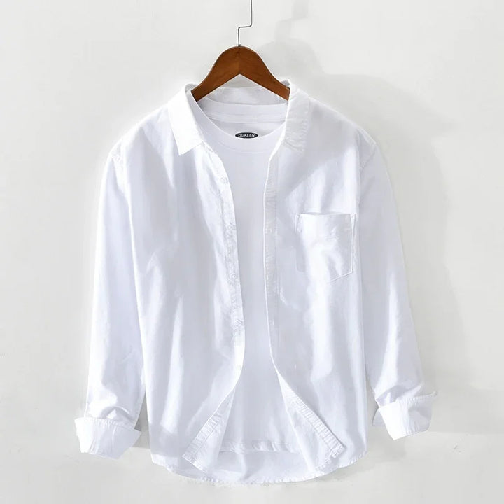 White casual long-sleeve button-up shirt layered over white crew neck t-shirt hanging on wooden hanger