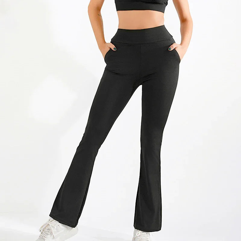 Woman wearing black high-waisted flare leggings with pockets and white sneakers on white background