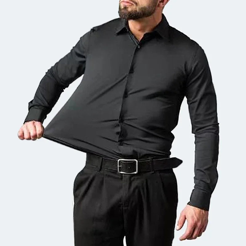 Man wearing black fitted dress shirt stretching fabric to show elasticity against white background