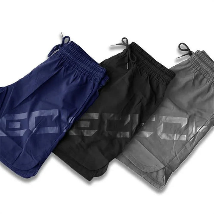 Three men's athletic shorts in navy, black, and gray with drawstrings and bold side lettering.