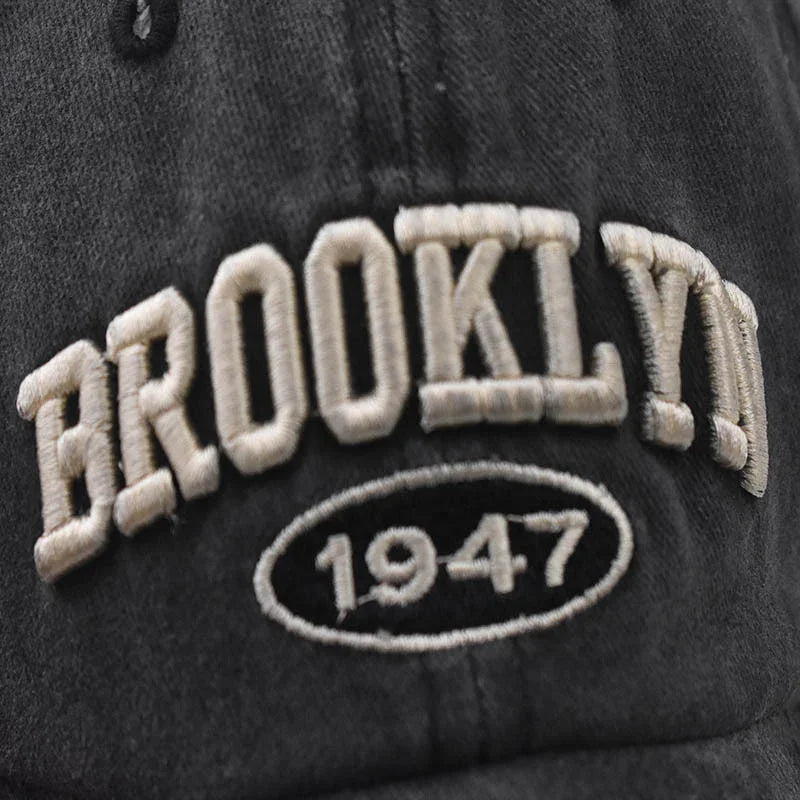 Close-up of black cap with white embroidered text 'BROOKLYN' and '1947' oval design