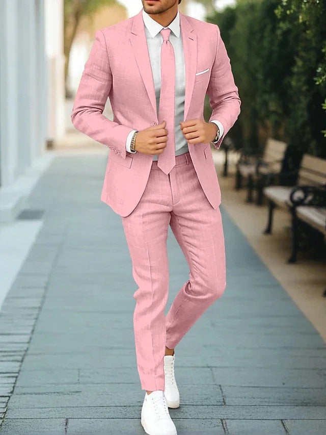 Man wearing a slim-fit pink suit with matching tie, white shirt, and white sneakers outdoors