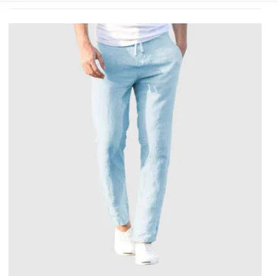 Man wearing light blue slim-fit jogger pants and white sneakers on plain background