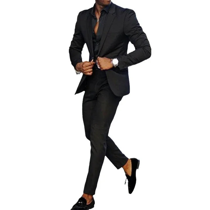Man wearing a stylish slim-fit black suit with black loafers and a wristwatch