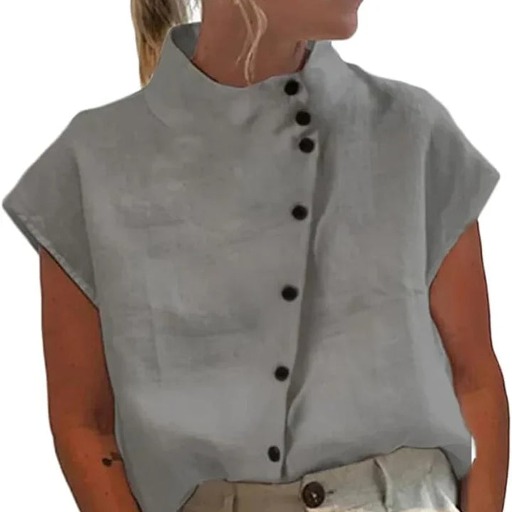woman wearing light gray sleeveless blouse with high collar and black buttons on front