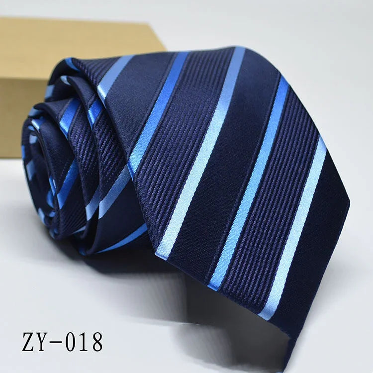 Rolled navy blue tie with light blue diagonal stripes on white surface with brown box