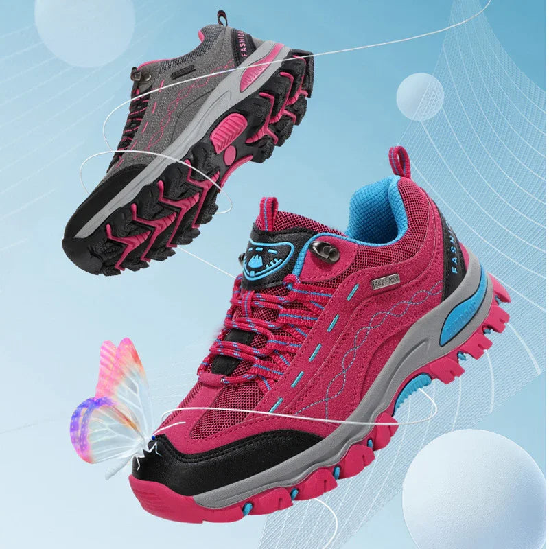 Pink and gray fashion trail running shoes with blue accents and rugged soles against a blue background