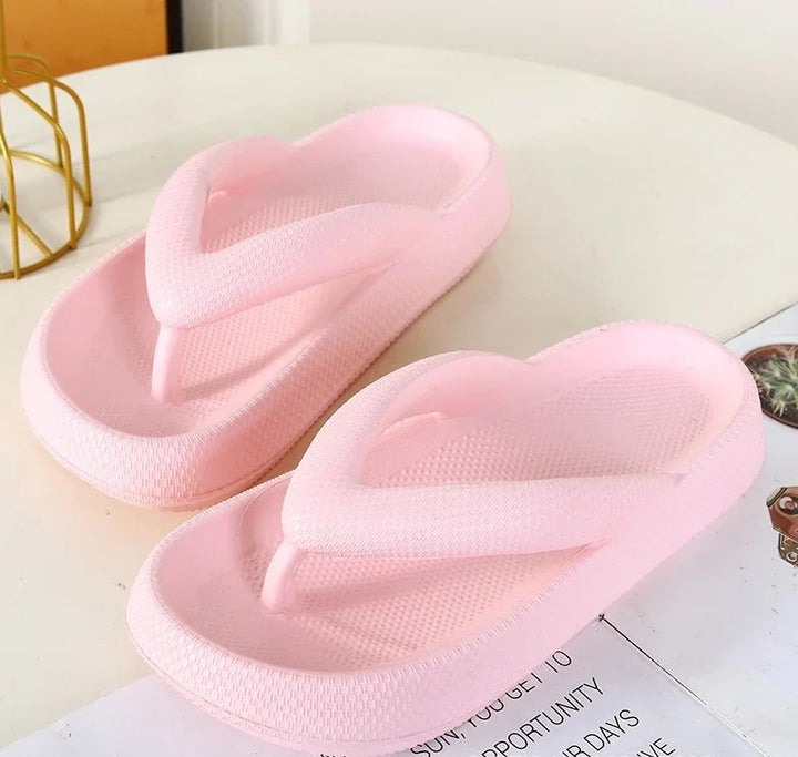 Light pink cushioned flip-flop sandals with thick straps on a white surface