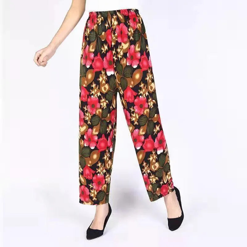 Woman wearing wide-leg floral print pants with red, green, and brown flowers and black heels