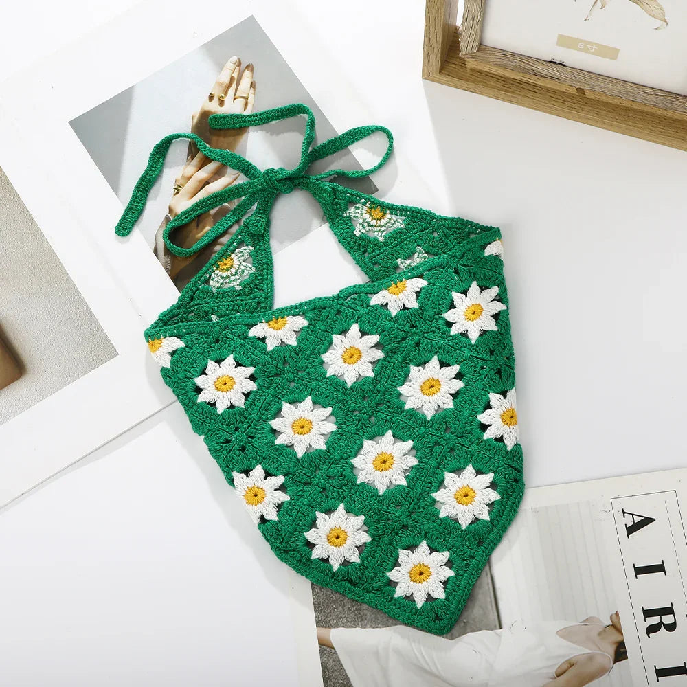 Green crochet halter top with white daisy flower patterns laid on white surface with fashion images