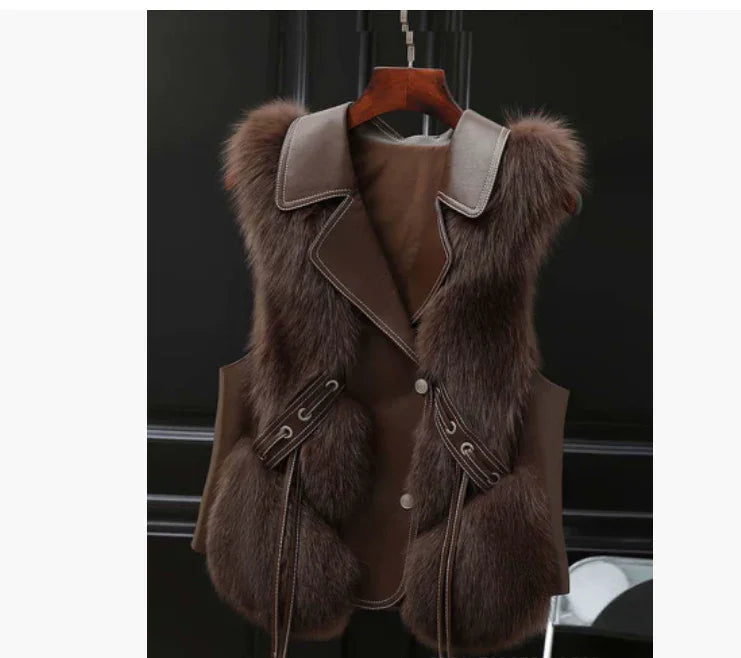 Brown faux fur vest with leather collar and trim hanging on wooden hanger