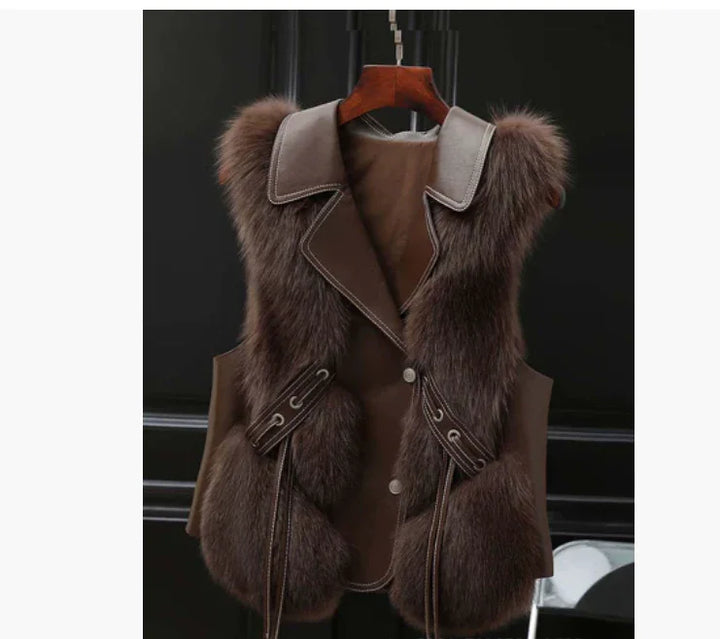 Brown faux fur vest with leather collar and trim hanging on wooden hanger