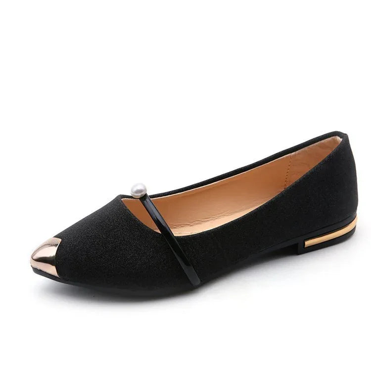 Black flat shoe with gold metallic toe cap, pearl-accented strap, and gold detail on heel