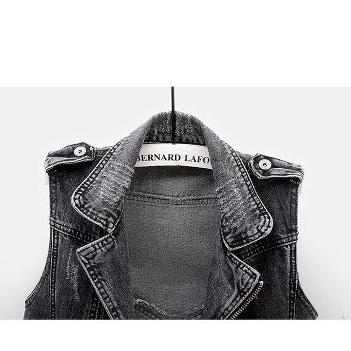 Black denim sleeveless jacket with collar and shoulder buttons hanging on a Bernard Lafond hanger