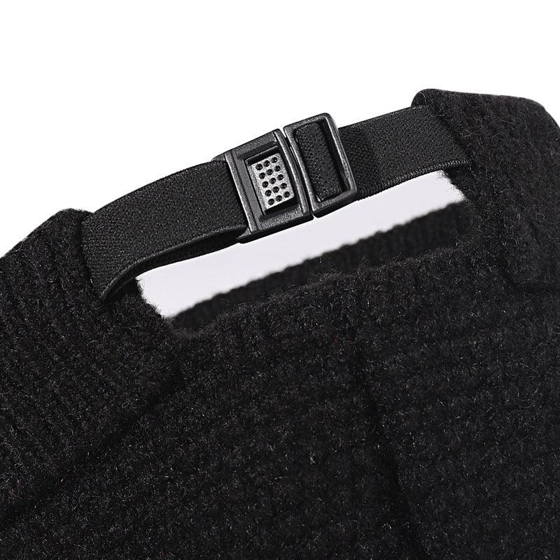 Close-up of adjustable black strap with plastic buckle on textured black knit fabric