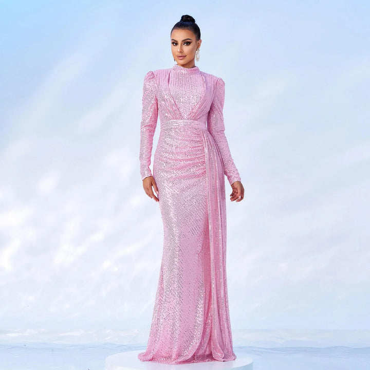 Woman wearing a long pink sequin evening gown with long sleeves and high neck on white background