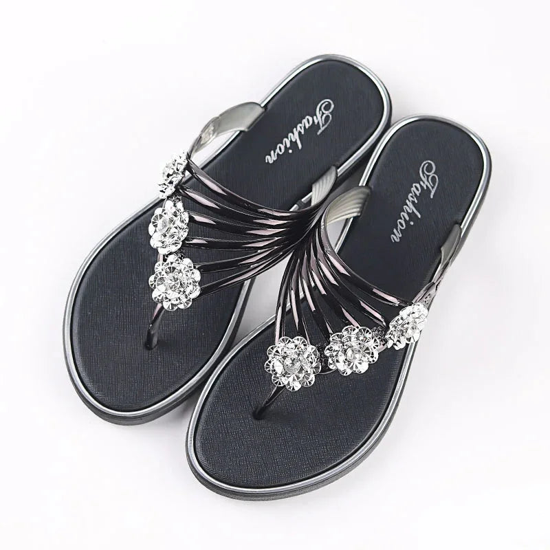 Black women's flip-flops with silver decorative flower embellishments on straps, branded sole