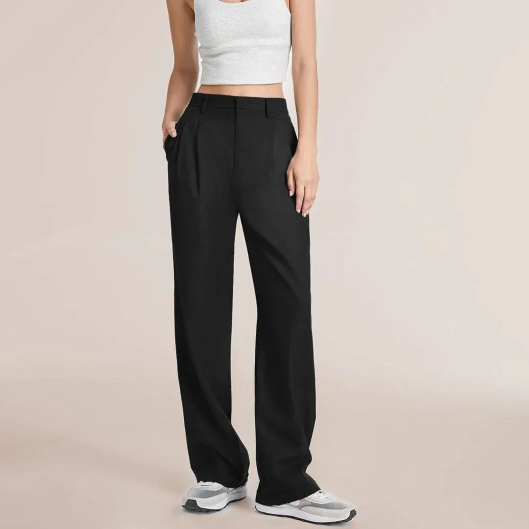Woman wearing black high-waisted wide-leg pants with white sneakers and a white crop top