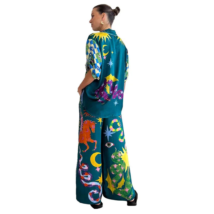Woman in colorful celestial print outfit with sun, moon, stars, snakes, and horse designs on teal fabric