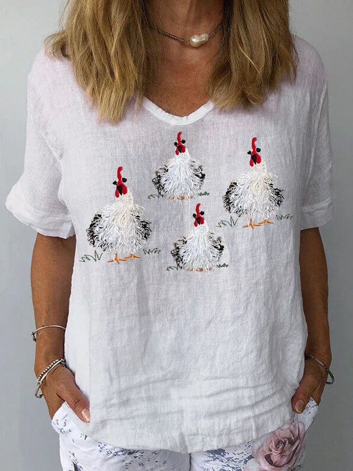 Woman wearing white linen shirt with embroidered fluffy chickens and casual flower print pants