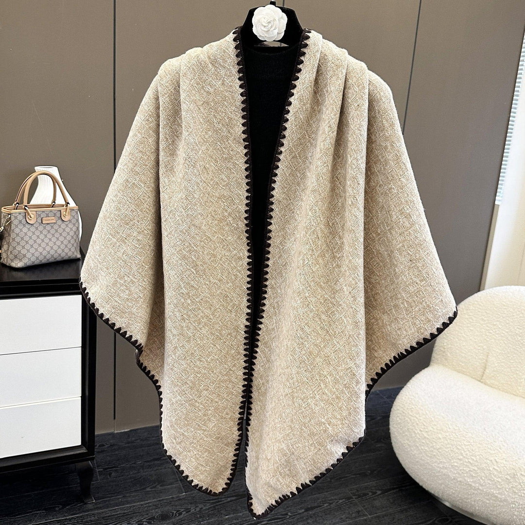 Beige textured shawl with black trim displayed on a black mannequin in a modern room