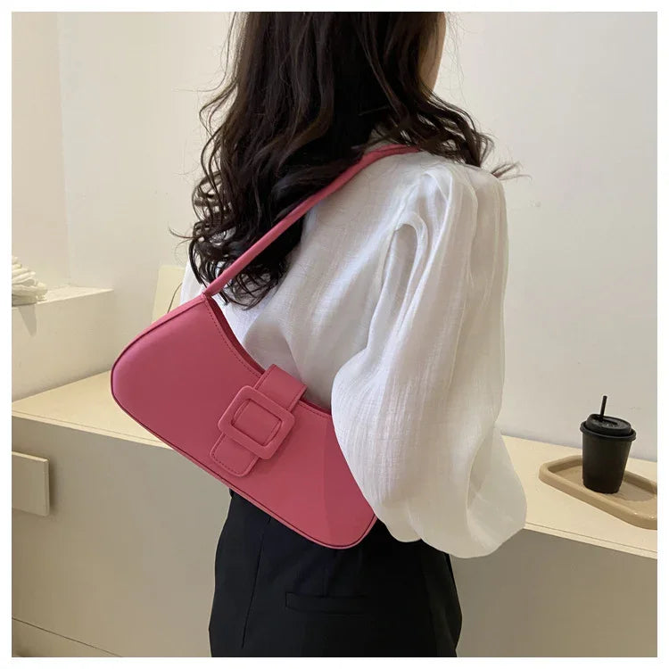 Woman wearing white blouse and black pants carrying a pink shoulder bag with buckle
