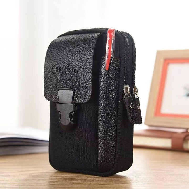 Compact black fabric and leather pouch with dual zippered compartments and front buckle pocket holding a red pen