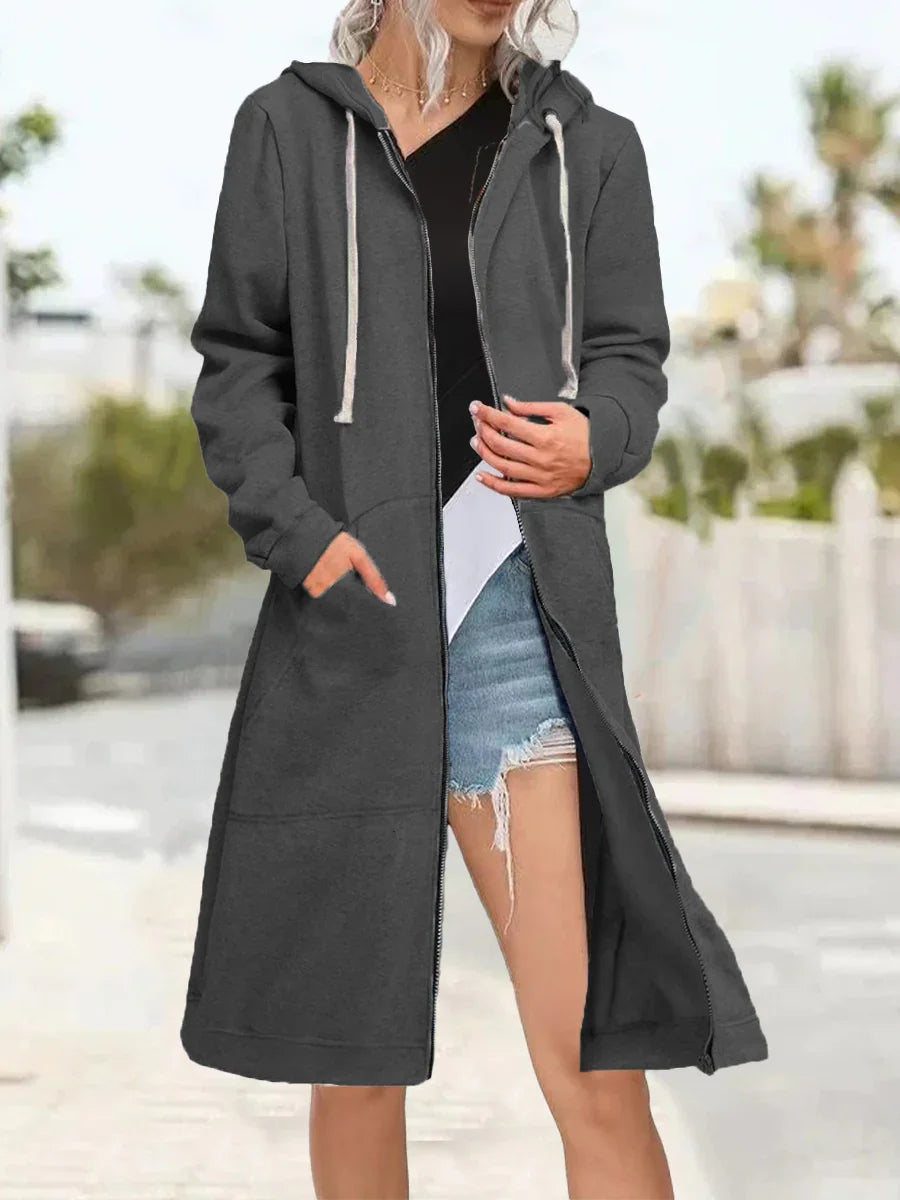 Woman wearing long dark gray zip-up hooded sweatshirt with white drawstrings outdoors