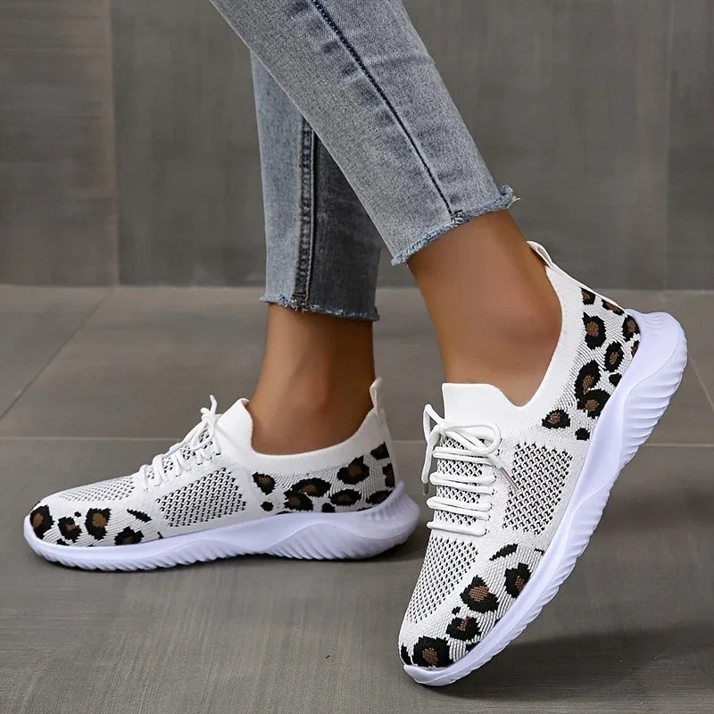 White knitted sneakers with leopard print detail worn with light blue skinny jeans on gray floor