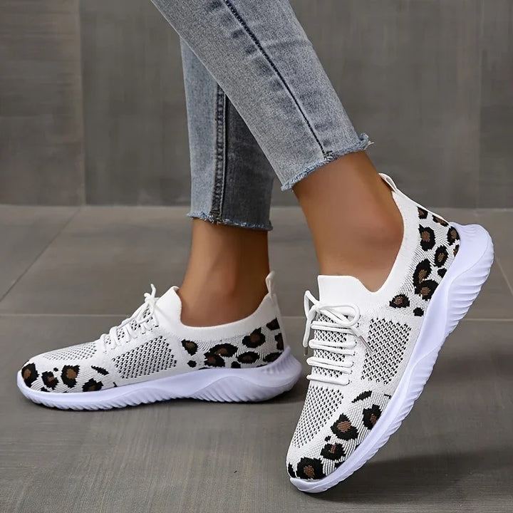 White knitted sneakers with leopard print detail worn with light blue skinny jeans on gray floor