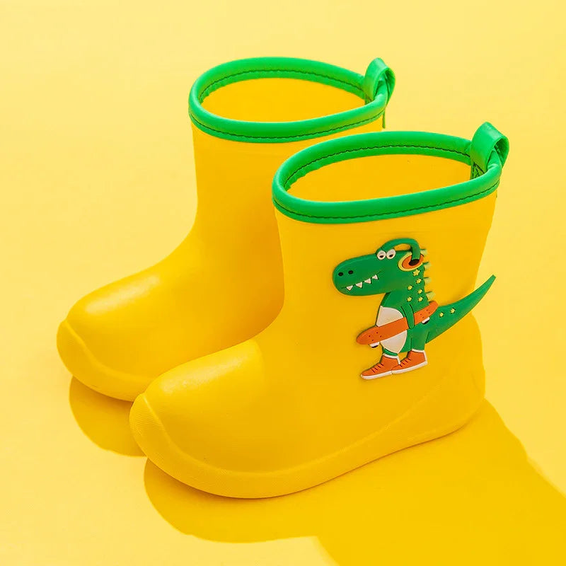 Yellow toddler rain boots with green trim and dinosaur design on a yellow background