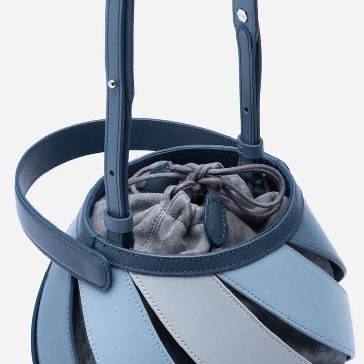 Blue leather bucket bag with adjustable strap and gray drawstring pouch inside