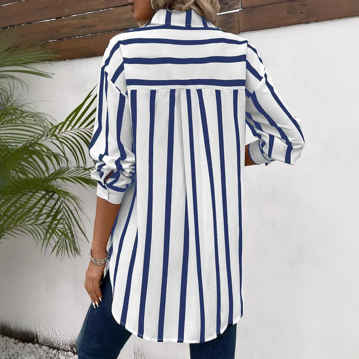 Woman wearing long-sleeve white shirt with vertical navy blue stripes, standing outdoors