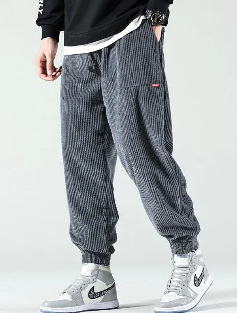 Person wearing gray ribbed jogger pants with elastic cuffs and white high-top sneakers