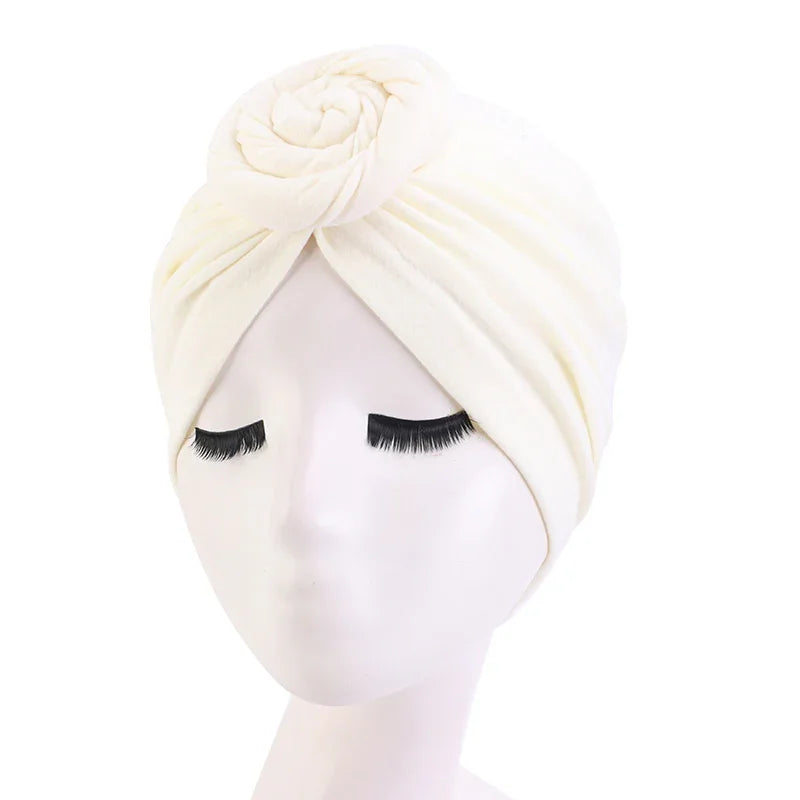White turban headwrap with rose detail on mannequin with long eyelashes